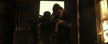 Movie still from “War for the Planet of the Apes” (2017), directed by Matt Reeves – A man in a gorilla suit holding a monkey; Medium shot, Low angle
