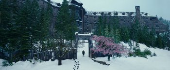 Movie still from “War for the Planet of the Apes” (2017), directed by Matt Reeves – A person walking in the snow near a building; Extreme Wide shot, High angle