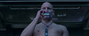 Movie still from “War for the Planet of the Apes” (2017), directed by Matt Reeves – A bald man is holding a cell phone up to his face; Close Up shot, Low angle