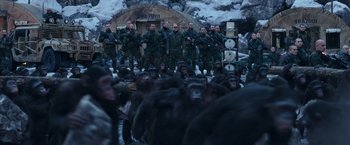 Movie still from “War for the Planet of the Apes” (2017), directed by Matt Reeves – A group of men standing next to each other in front of a group of chimpanzees; Wide shot, Low angle