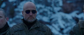 Movie still from “War for the Planet of the Apes” (2017), directed by Matt Reeves – A man with a bald head wearing sunglasses; Close Up shot, Low angle
