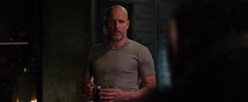 Movie still from “War for the Planet of the Apes” (2017), directed by Matt Reeves – A bald man in a gray shirt is holding a cup; Medium shot, Over the shoulder angle