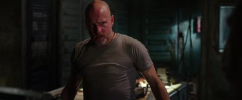 Movie still from “War for the Planet of the Apes” (2017), directed by Matt Reeves – A man with a shaved head and a beard is standing; Medium shot, Low angle