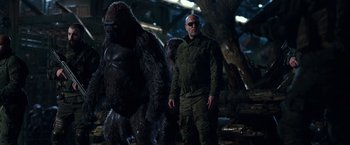 Movie still from “War for the Planet of the Apes” (2017), directed by Matt Reeves – A man and a gorilla standing next to each other; Medium shot, Low angle