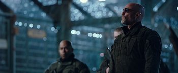 Movie still from “War for the Planet of the Apes” (2017), directed by Matt Reeves – A man standing next to another man wearing glasses; Medium shot, Low angle