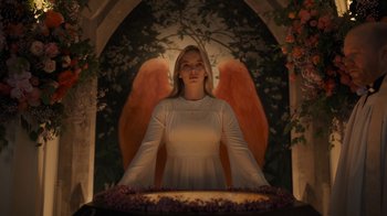 Movie still from “Killing Eve” (2018), created by Phoebe Waller-Bridge – A woman in a white dress with a halo around her neck; Medium shot, Low angle