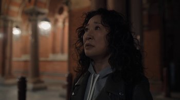 Movie still from “Killing Eve” (2018), created by Phoebe Waller-Bridge – A woman with curly hair is looking upward; Close Up shot, Over the shoulder angle