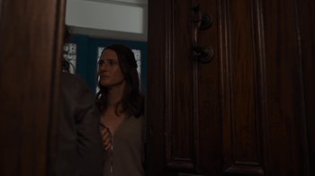 Movie still from “Killing Eve” (2018), created by Phoebe Waller-Bridge – A woman standing in front of a wooden door; Medium shot, Over the shoulder angle