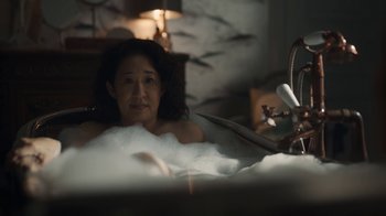 Movie still from “Killing Eve” (2018), created by Phoebe Waller-Bridge – A woman sitting in a bath tub in a room; Medium shot, High angle