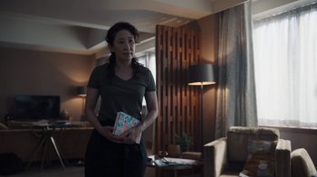 Movie still from “Killing Eve” (2018), created by Phoebe Waller-Bridge – A woman holding a book in her hands; Medium shot, Over the shoulder angle