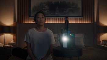 Movie still from “Killing Eve” (2018), created by Phoebe Waller-Bridge – A woman sitting in front of a lamp in a living room; Medium shot, High angle