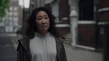 Movie still from “Killing Eve” (2018), created by Phoebe Waller-Bridge – An older woman wearing a gray sweatshirt and a brown jacket; Close Up shot, Over the shoulder angle