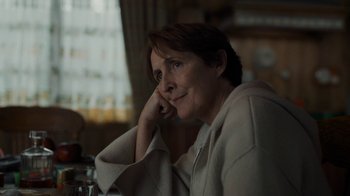 Movie still from “Killing Eve” (2018), created by Phoebe Waller-Bridge – A woman sitting at a table with her head resting on her hand; Close Up shot, Over the shoulder angle