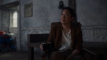 Movie still from “Killing Eve” (2018), created by Phoebe Waller-Bridge – A woman sitting in a chair holding a mug; Medium shot, Over the shoulder angle