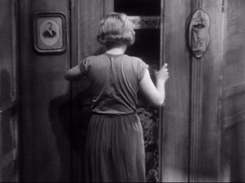 Movie still from “L'Atalante” (1934), directed by Jean Vigo – A black and white photo of a woman opening a door; Medium shot, High angle