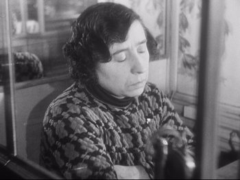 Movie still from “L'Atalante” (1934), directed by Jean Vigo – An old black and white photo of a woman sitting in a chair; Close Up shot, High angle
