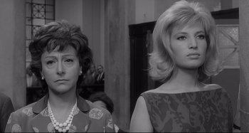 Movie still from “L'Eclisse” (1962), directed by Michelangelo Antonioni – Two women standing next to each other in front of a crowd; Close Up shot, Low angle