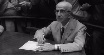 Movie still from “L'Eclisse” (1962), directed by Michelangelo Antonioni – An older man is writing on a piece of paper; Close Up shot, High angle