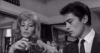 Movie still from “L'Eclisse” (1962), directed by Michelangelo Antonioni – A man and a woman are looking at something in their hands; Close Up shot, Low angle