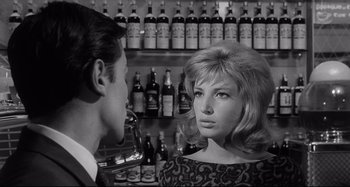 Movie still from “L'Eclisse” (1962), directed by Michelangelo Antonioni – A man and a woman in front of bottles of alcohol; Close Up shot, Over the shoulder angle