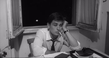 Movie still from “L'Eclisse” (1962), directed by Michelangelo Antonioni – Black and white photograph of a man sitting at a table; Close Up shot, High angle