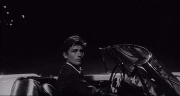 Movie still from “L'Eclisse” (1962), directed by Michelangelo Antonioni – A young man sitting in the driver's seat of a car; Close Up shot, High angle