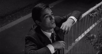 Movie still from “L'Eclisse” (1962), directed by Michelangelo Antonioni – Black and white photograph of a man leaning on a fence; Close Up shot, Low angle