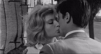 Movie still from “L'Eclisse” (1962), directed by Michelangelo Antonioni – A man and a woman kissing each other in front of a brick wall; Close Up shot, Low angle