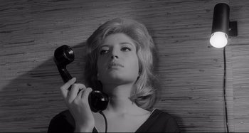 Movie still from “L'Eclisse” (1962), directed by Michelangelo Antonioni – A woman holding up a black phone to her ear; Close Up shot, High angle