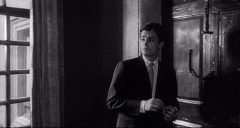 Movie still from “L'Eclisse” (1962), directed by Michelangelo Antonioni – A black and white photo of a man in a suit and tie; Medium shot, Low angle
