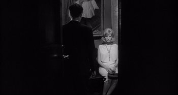 Movie still from “L'Eclisse” (1962), directed by Michelangelo Antonioni – A man and a woman sitting in a doorway; Medium shot, Over the shoulder angle