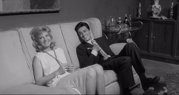 Movie still from “L'Eclisse” (1962), directed by Michelangelo Antonioni – A man and a woman sitting on a couch in a living room; Medium shot, Low angle