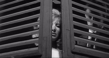 Movie still from “L'Eclisse” (1962), directed by Michelangelo Antonioni – A woman looking out a window through a pair of louvered shutters; Close Up shot, Low angle