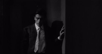 Movie still from “L'Eclisse” (1962), directed by Michelangelo Antonioni – A black and white photo of a man wearing a suit and tie; Medium shot, Low angle