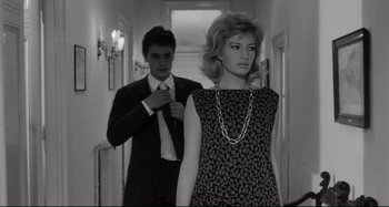 Movie still from “L'Eclisse” (1962), directed by Michelangelo Antonioni – A man and a woman standing in a hallway; Medium shot, Low angle