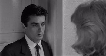 Movie still from “L'Eclisse” (1962), directed by Michelangelo Antonioni – A man in a suit and tie looking at a woman in a dress suit; Close Up shot, Over the shoulder angle