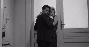 Movie still from “L'Eclisse” (1962), directed by Michelangelo Antonioni – A man and a woman hugging in front of a door; Medium shot, Low angle