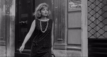 Movie still from “L'Eclisse” (1962), directed by Michelangelo Antonioni – A black and white photo of a woman walking down the street; Medium shot, Low angle