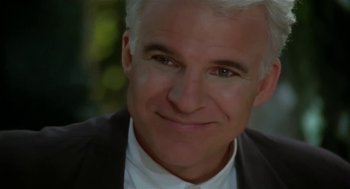 Movie still from “L.A. Story” (1991), directed by Mick Jackson – A person wearing a suit and tie; Close Up shot, Over the shoulder angle