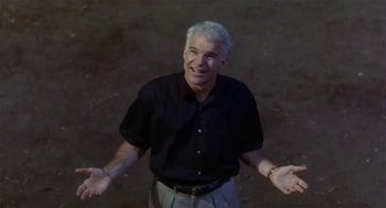 Movie still from “L.A. Story” (1991), directed by Mick Jackson – An older man standing with his arms outstretched; Medium shot, Low angle