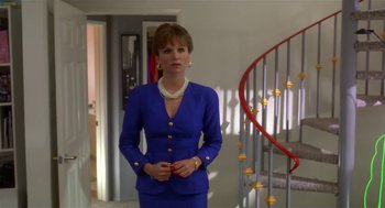 Movie still from “L.A. Story” (1991), directed by Mick Jackson – A woman in a blue suit standing in front of a spiral staircase; Medium shot, Low angle