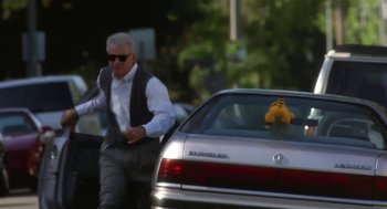 Movie still from “L.A. Story” (1991), directed by Mick Jackson – A man walking down a street next to a parked car; Medium shot, Low angle