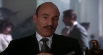 Movie still from “L.A. Story” (1991), directed by Mick Jackson – A man in a suit and tie with a goatee; Close Up shot, Over the shoulder angle