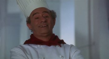 Movie still from “L.A. Story” (1991), directed by Mick Jackson – A man in a chef's outfit smiling for the camera; Close Up shot, Low angle