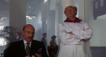 Movie still from “L.A. Story” (1991), directed by Mick Jackson – A man in a chef's outfit standing next to another man in a suit and tie; Medium shot, Low angle