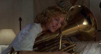 Movie still from “L.A. Story” (1991), directed by Mick Jackson – A woman is holding a trombone and smiling for the camera; Close Up shot, Low angle