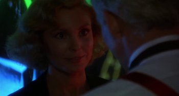 Movie still from “L.A. Story” (1991), directed by Mick Jackson – A young woman smiles at the camera in a dark room; Close Up shot, Over the shoulder angle