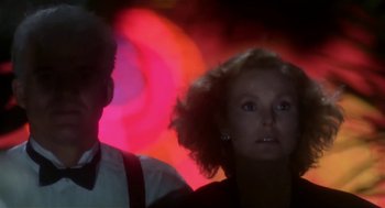 Movie still from “L.A. Story” (1991), directed by Mick Jackson – A man and a woman are standing in front of a red light; Close Up shot, Low angle