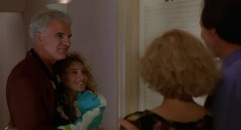 Movie still from “L.A. Story” (1991), directed by Mick Jackson – A man and a woman standing next to each other in a room; Medium shot, Over the shoulder angle