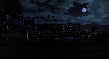 Movie still from “L.A. Story” (1991), directed by Mick Jackson – A full moon rises over a city at night; Extreme Wide shot, Low angle